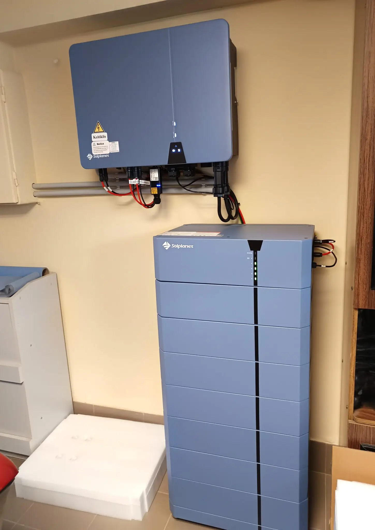 Grått batterilager montert under en inverter på veggen