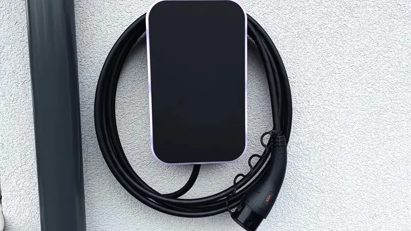 Svart elbillader med kabel på en hvit vegg